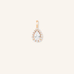 A gold-tone pendant featuring a pear-shaped diamond centerpiece encircled by smaller diamonds, set against a plain background.