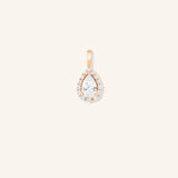 A gold-tone pendant featuring a pear-shaped diamond centerpiece encircled by smaller diamonds, set against a plain background.