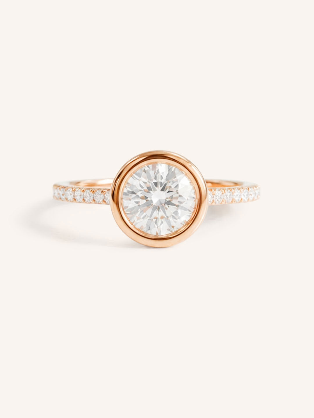 Rose gold round cut bezel set accented diamond engagement ring front view on white background