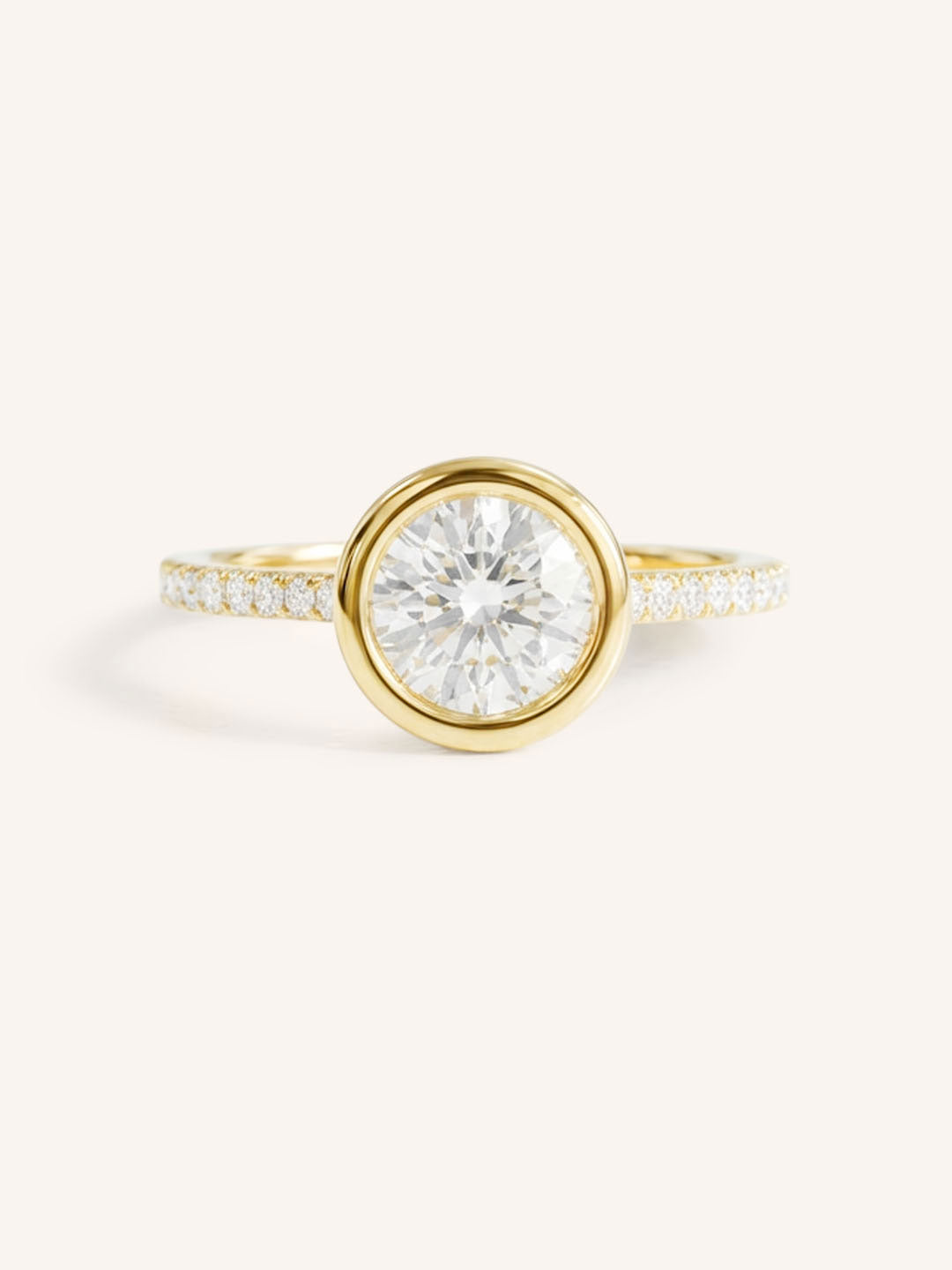 Yellow gold round cut bezel set accented diamond engagement ring front view on white background