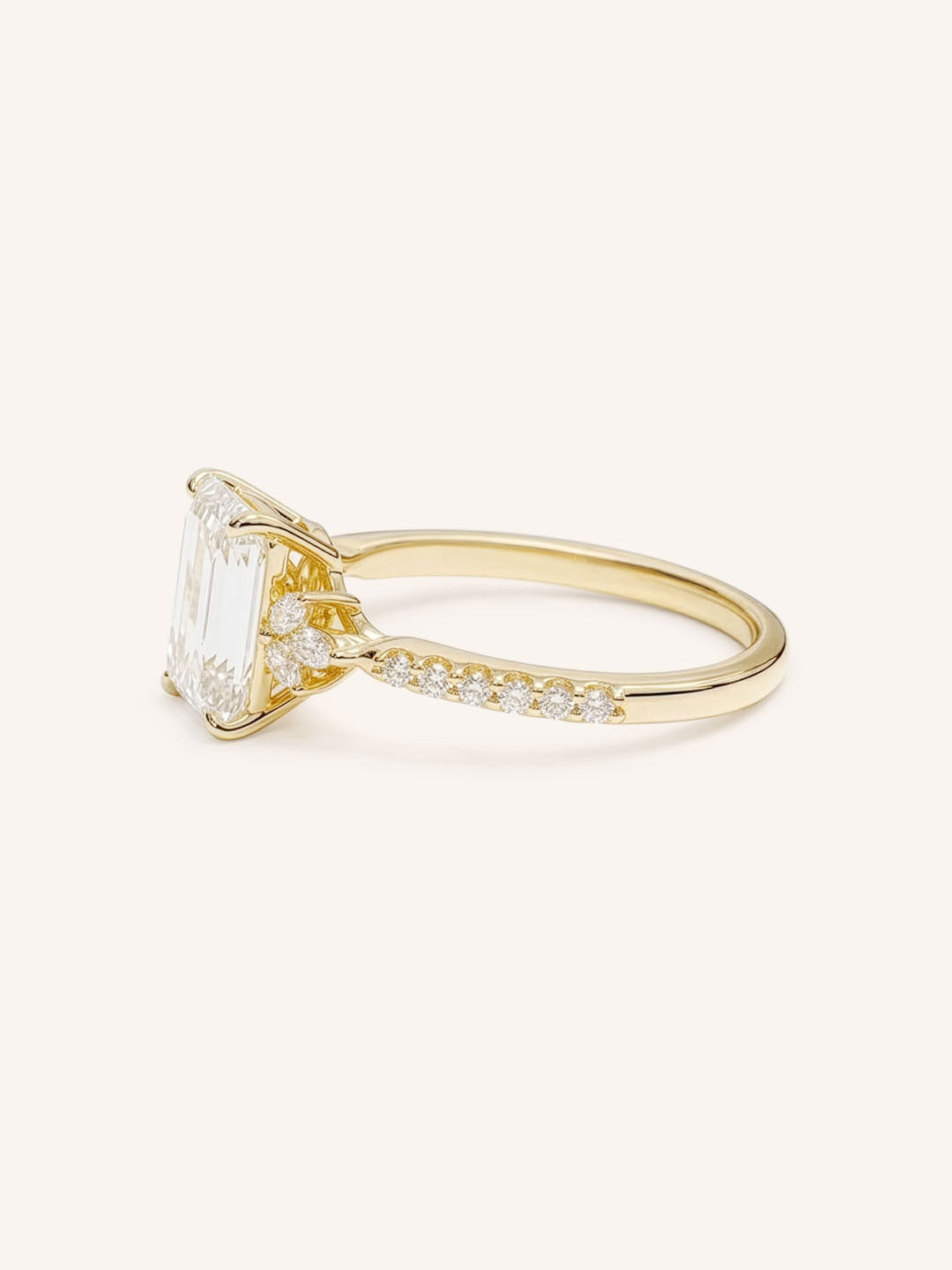 Yellow Gold emerald cut diamond engagement ring with pave band side view on white background