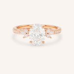 Rose gold oval-cut diamond engagement ring with marquise diamond accents on white background