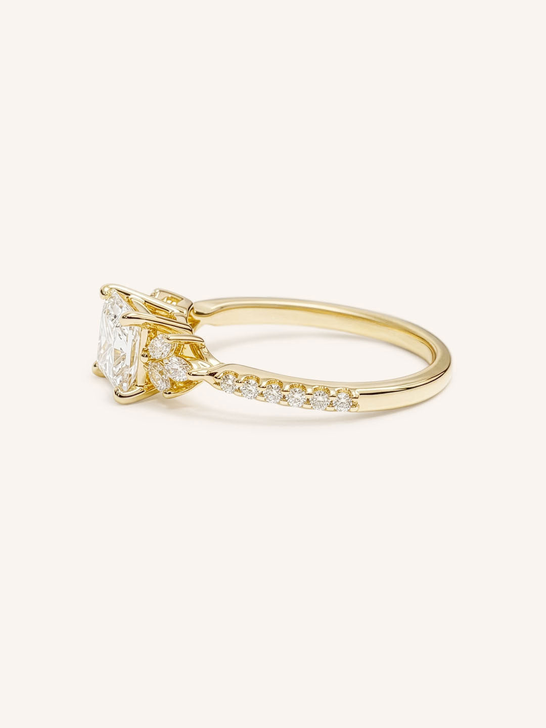 Yellow gold princess-cut diamond engagement ring with pavé band, side view on white background