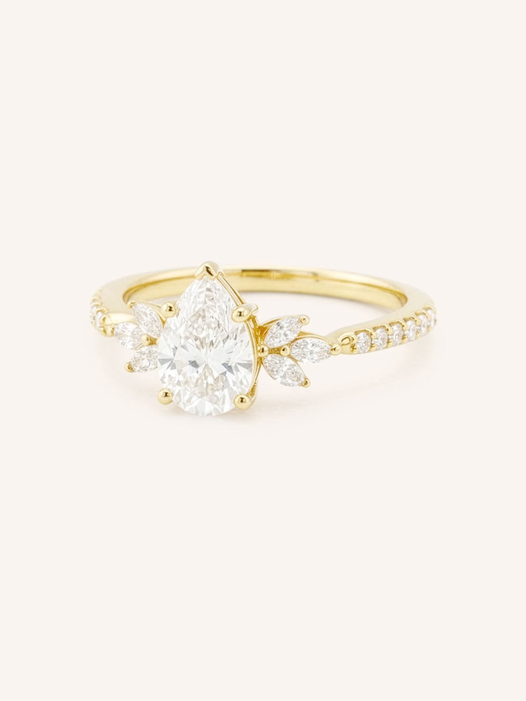 Yellow gold pear-cut diamond engagement ring with leaf-shaped diamond accents on the band, side view on white background