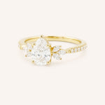 Yellow gold pear-cut diamond engagement ring with leaf-shaped diamond accents on the band, side view on white background