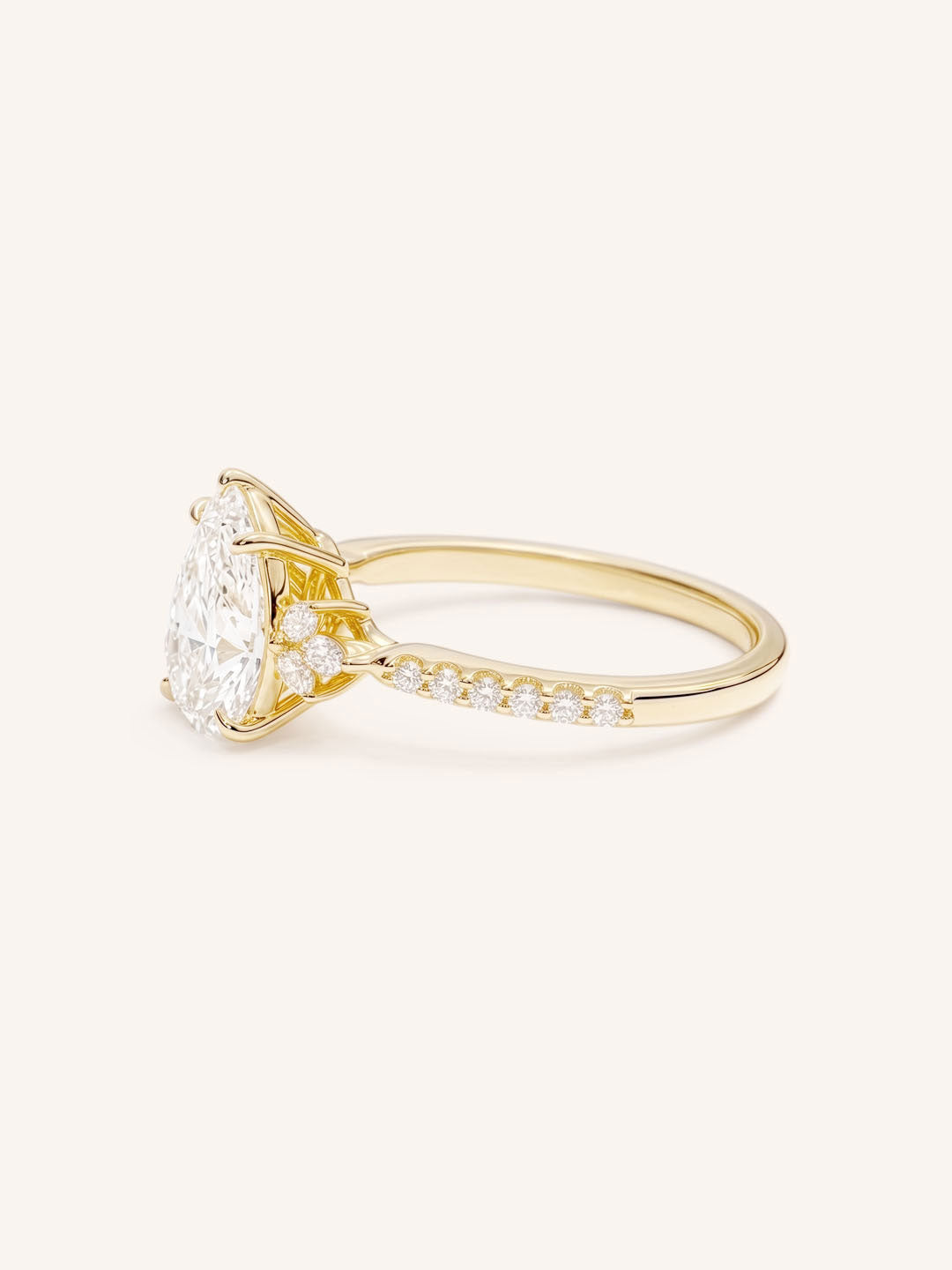 Yellow Gold pear diamond engagement ring with pave band side view on white background
