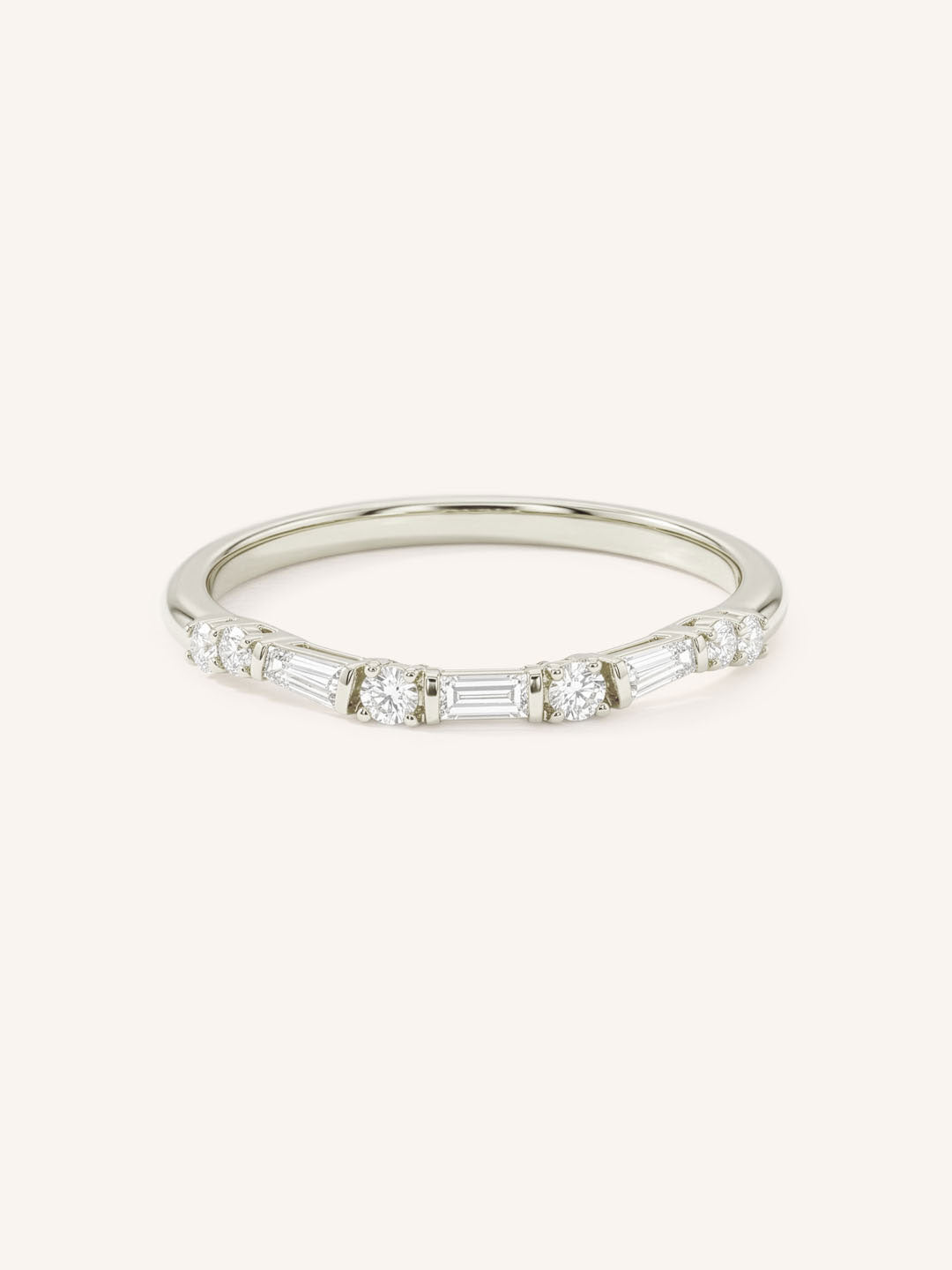 White gold curved diamond wedding band with alternating baguette and round diamonds on white background