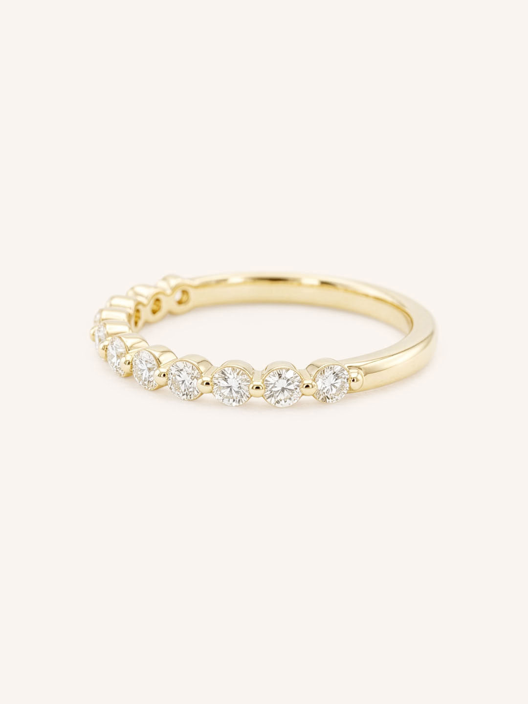Yellow gold wedding ring with a row of graduated round diamonds in prong settings, side view, on white background