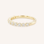 Yellow gold wedding ring with a row of graduated round diamonds in prong settings, side view, on white background