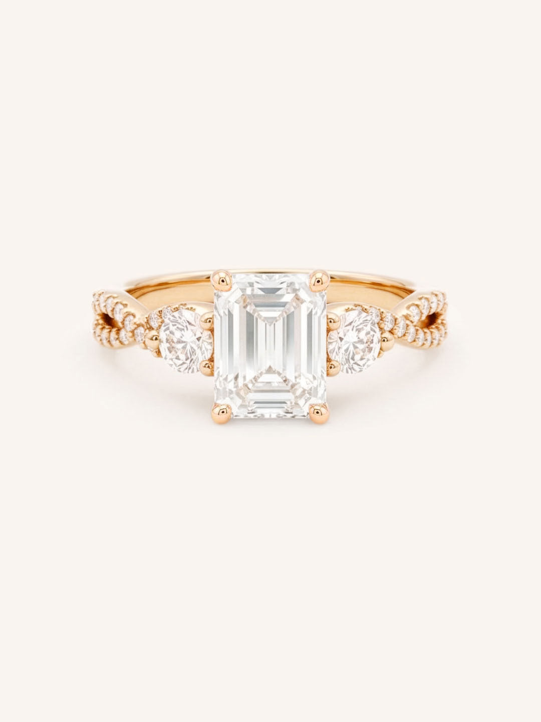 Rose gold Lindey emerald-cut three-stone diamond engagement ring with pave shoulders, front view, on white background