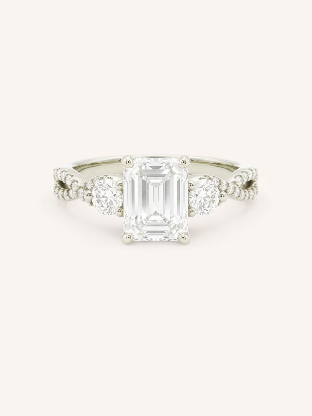 White gold emerald cut three stone diamond engagement ring with pave shoulders on white background