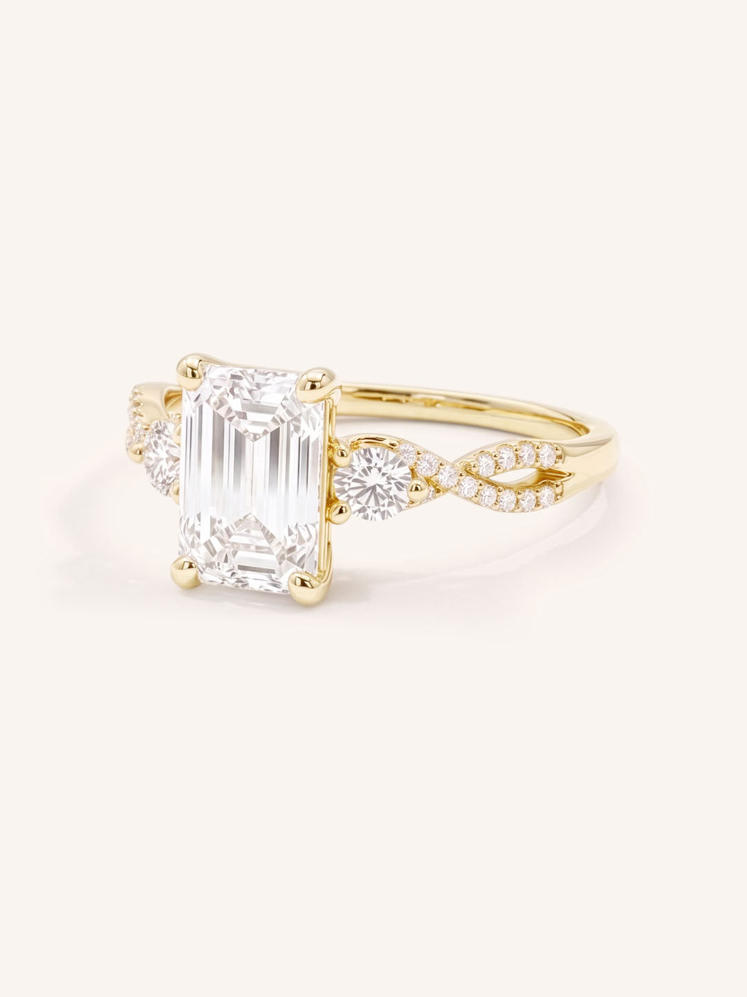 Yellow Gold emerald cut three stone diamond engagement ring with twisted pave band angled view on white background