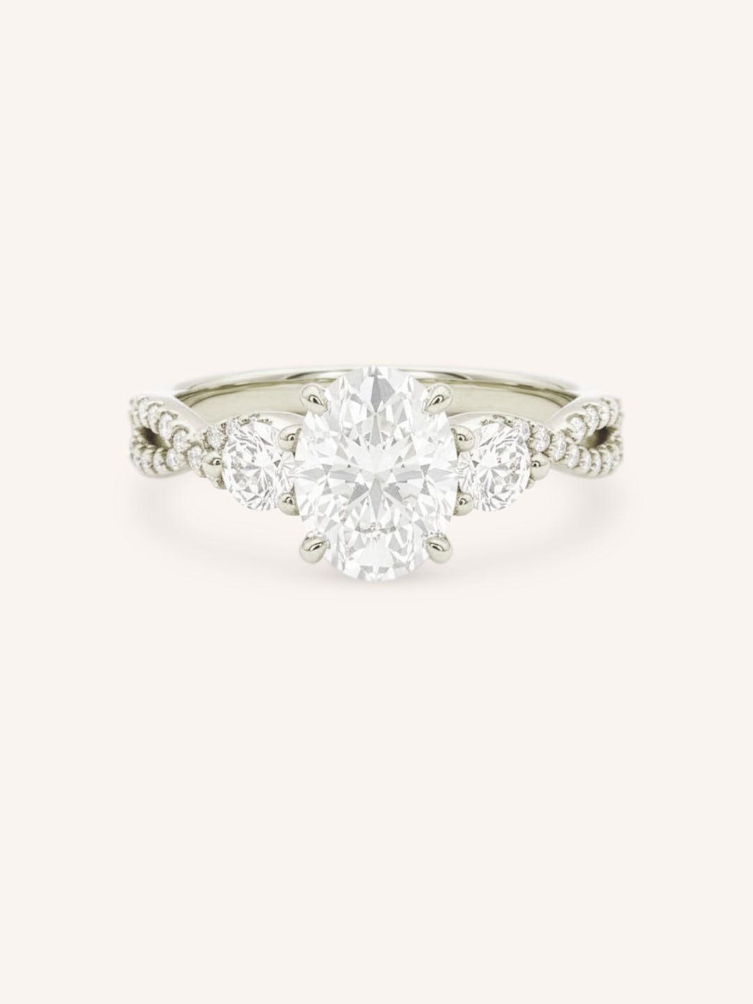 White gold oval cut three stone diamond engagement ring with pave shoulders on white background