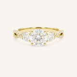 Yellow gold three-stone engagement ring with round-cut center diamond, round side diamonds, and twisted pave diamond shank, front view, on white background