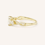 Yellow gold three-stone engagement ring with round-cut diamonds and twisted pave diamond shank, angled side view, on white background