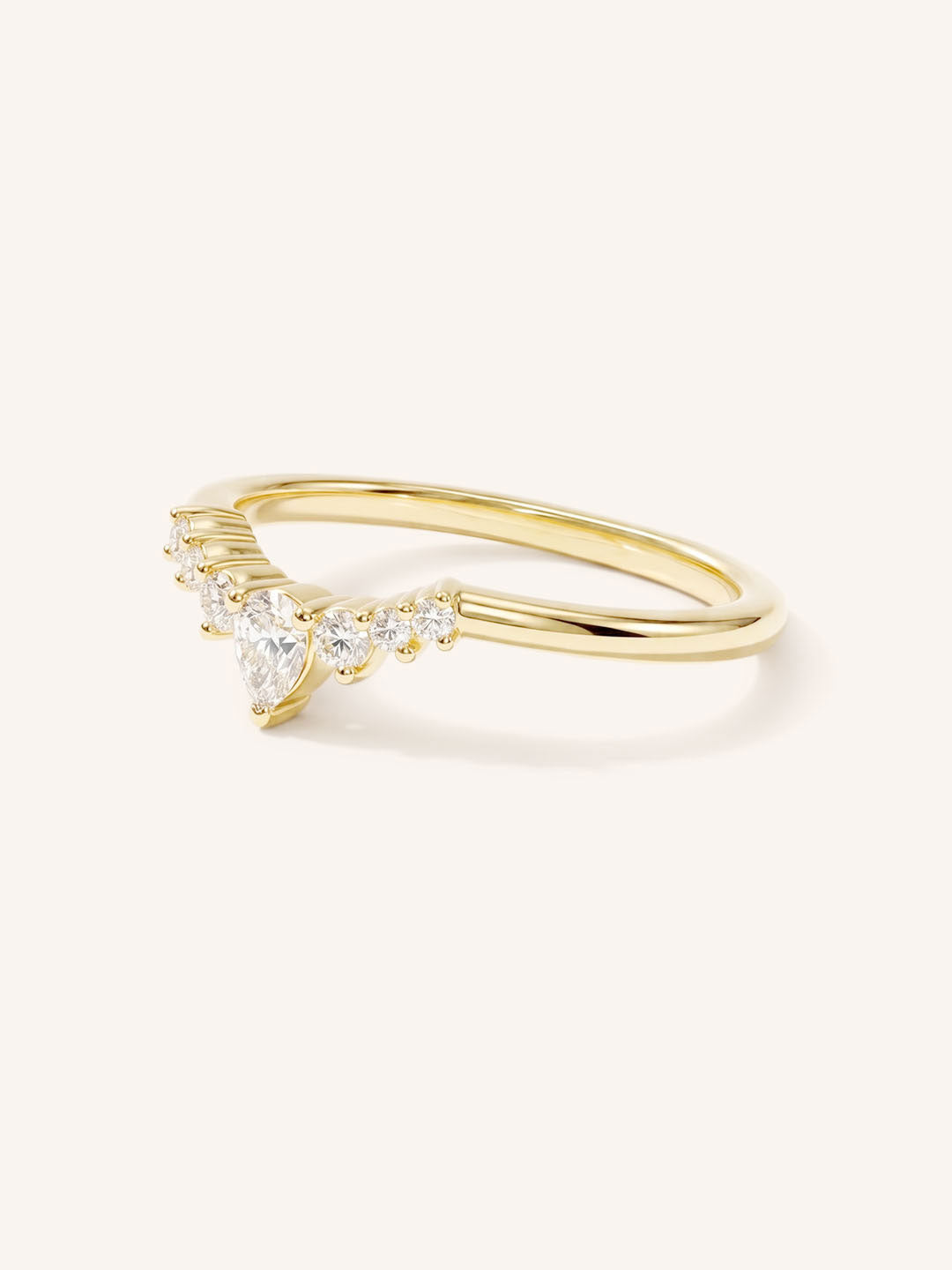 Yellow gold curved wedding band with pear-cut diamond and graduated round diamond accents on white background