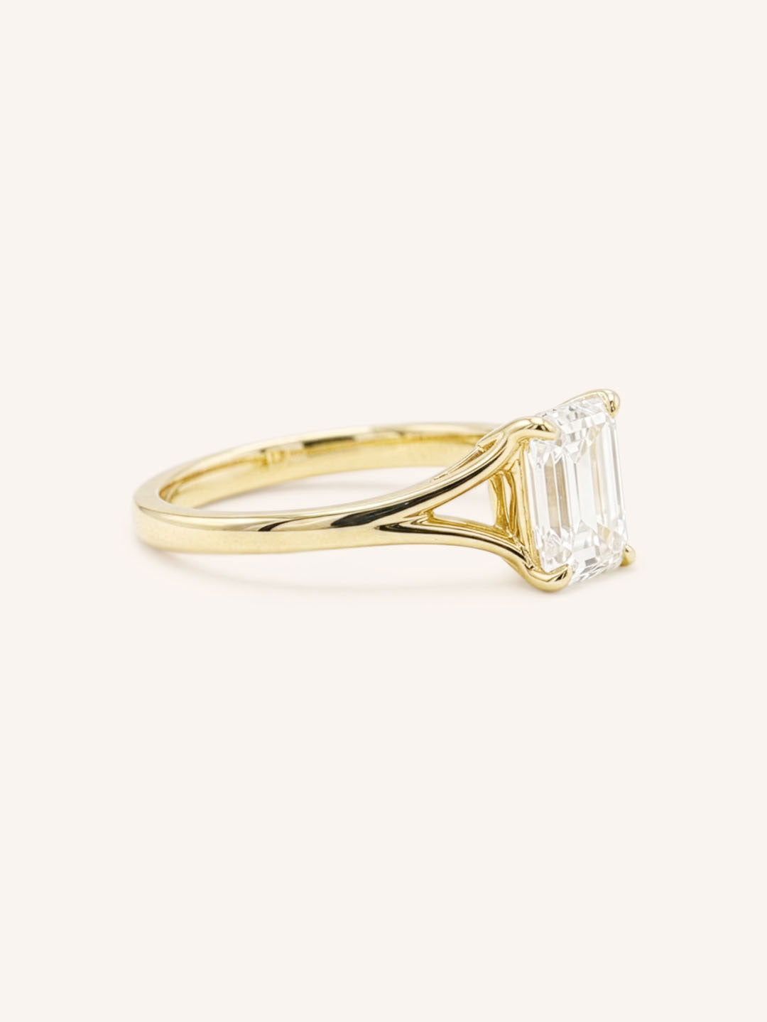 Yellow Gold emerald cut diamond split shank engagement ring side view on white background