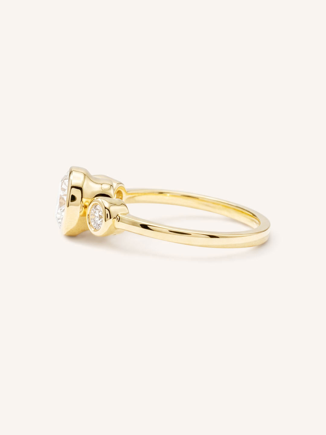 Yellow Gold Tamara Round Three Stone Diamond Bezel Engagement Ring side view on white background
