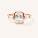 Rose gold Grannis emerald cut three stone and baguette diamond engagement ring front view on white background