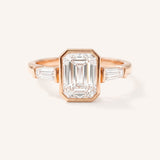 Rose gold Grannis emerald cut three stone and baguette diamond engagement ring front view on white background