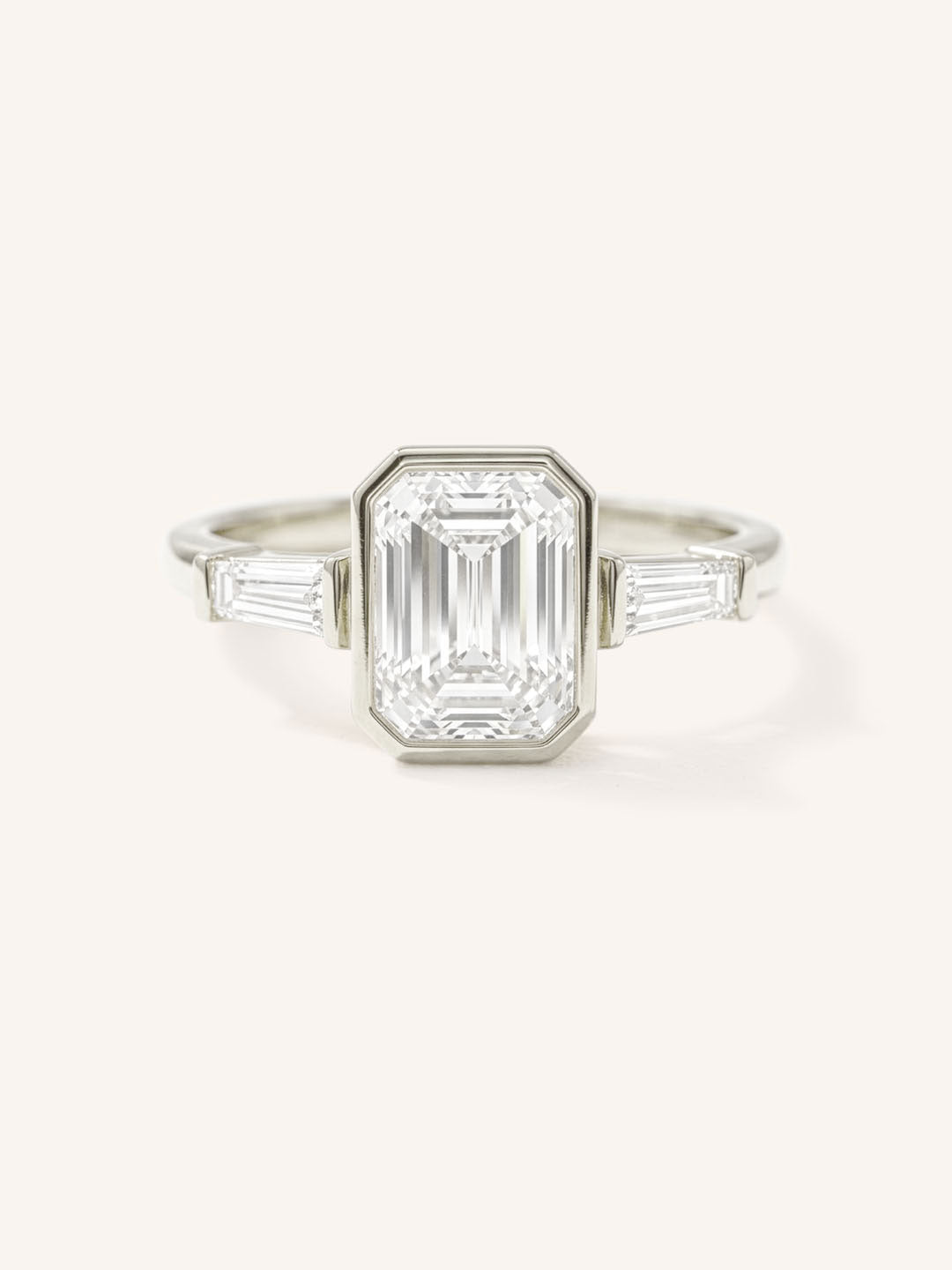 White gold Grannis emerald cut three stone and baguette diamond engagement ring front view on white background