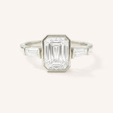 White gold Grannis emerald cut three stone and baguette diamond engagement ring front view on white background