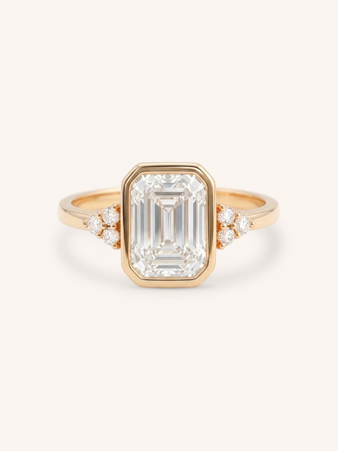 Rose gold emerald cut bezel set diamond engagement ring with side stones on white background