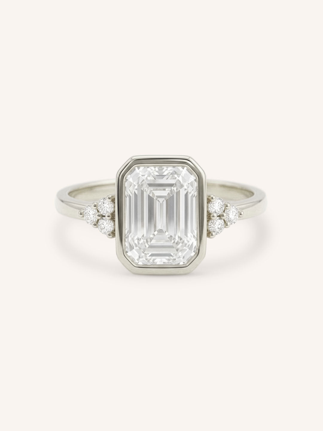 White gold emerald cut bezel set diamond engagement ring with side stones on white background