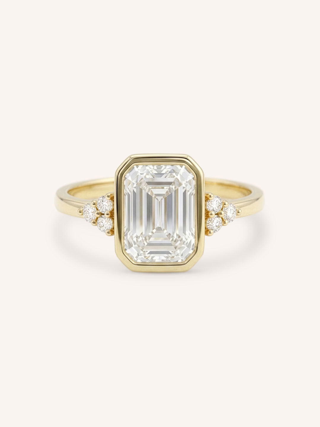 Yellow gold emerald cut bezel set diamond engagement ring with side stones on white background