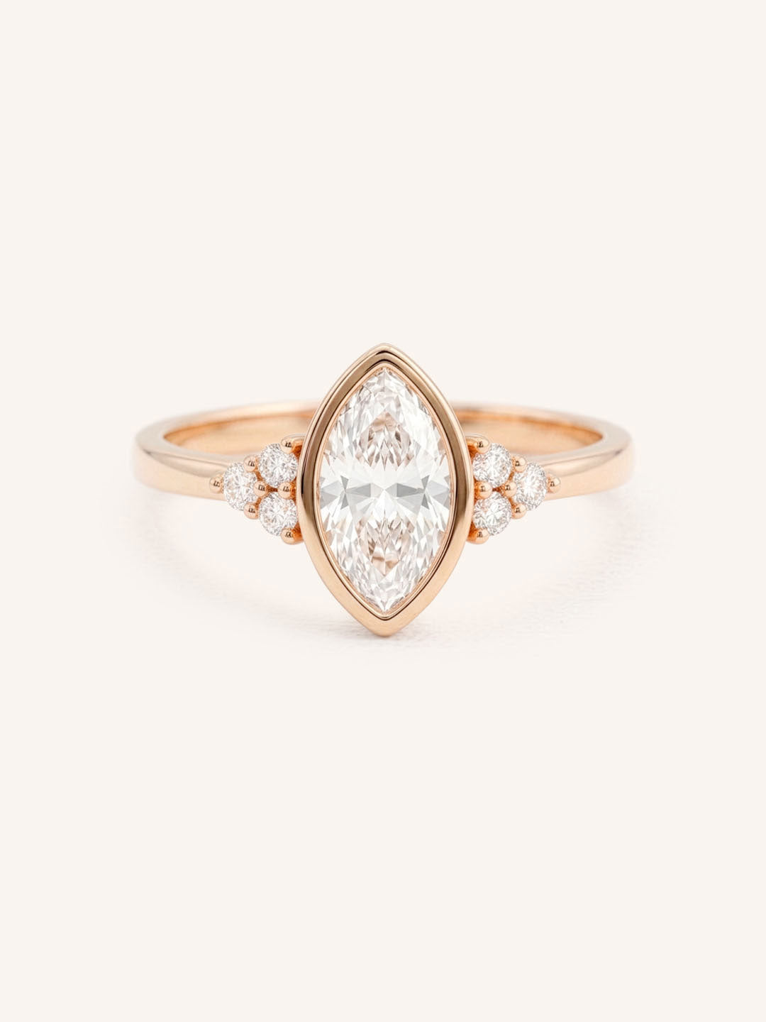 Rose gold marquise cut bezel set diamond engagement ring with side stones on white background