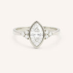 White gold marquise cut bezel set diamond engagement ring with side stones on white background
