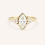 Yellow gold marquise cut bezel set diamond engagement ring with side stones on white background