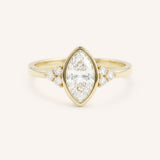 Yellow gold marquise cut bezel set diamond engagement ring with side stones on white background