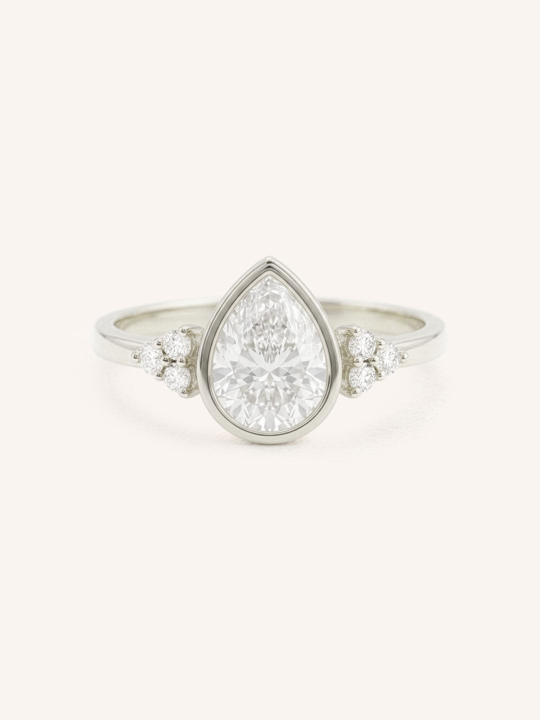 White gold pear cut bezel set diamond engagement ring with side stones on white background