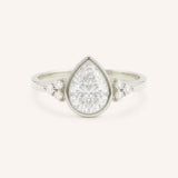 White gold pear cut bezel set diamond engagement ring with side stones on white background