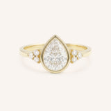 Yellow gold pear cut bezel set diamond engagement ring with side stones on white background
