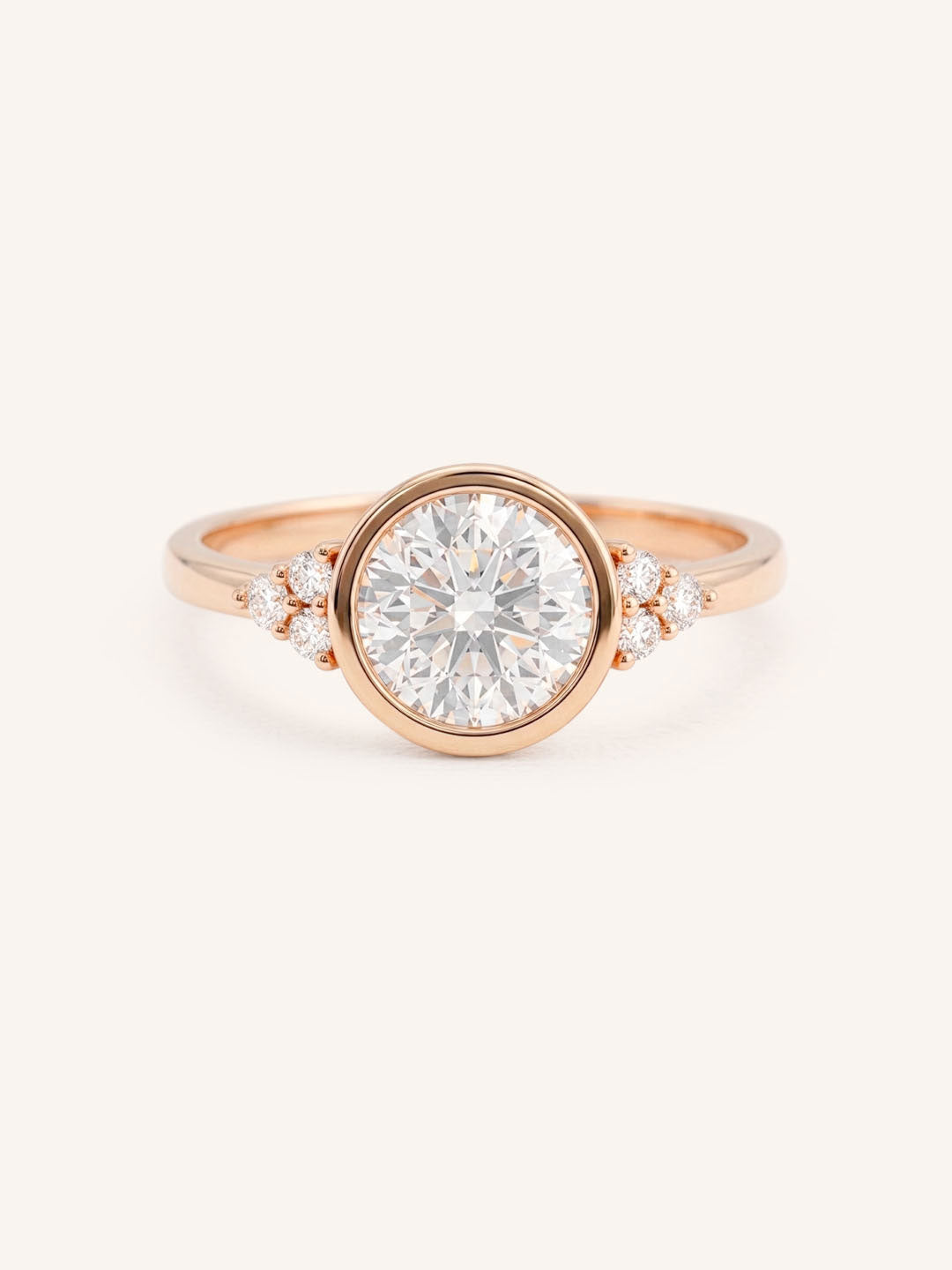 Rose gold round cut bezel set diamond engagement ring with side stones on white background