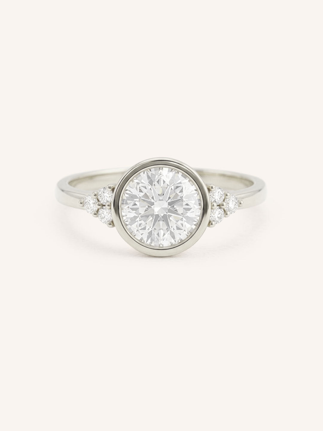 White gold round cut bezel set diamond engagement ring with side stones on white background