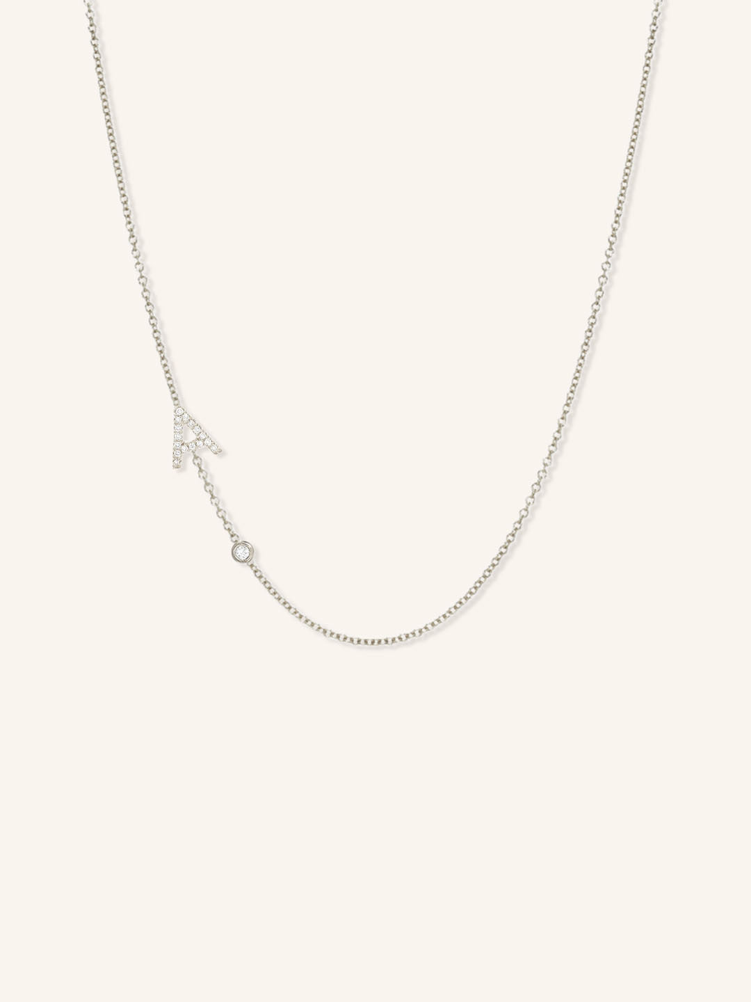 White gold asymmetrical diamond initial A and bezel necklace on white background