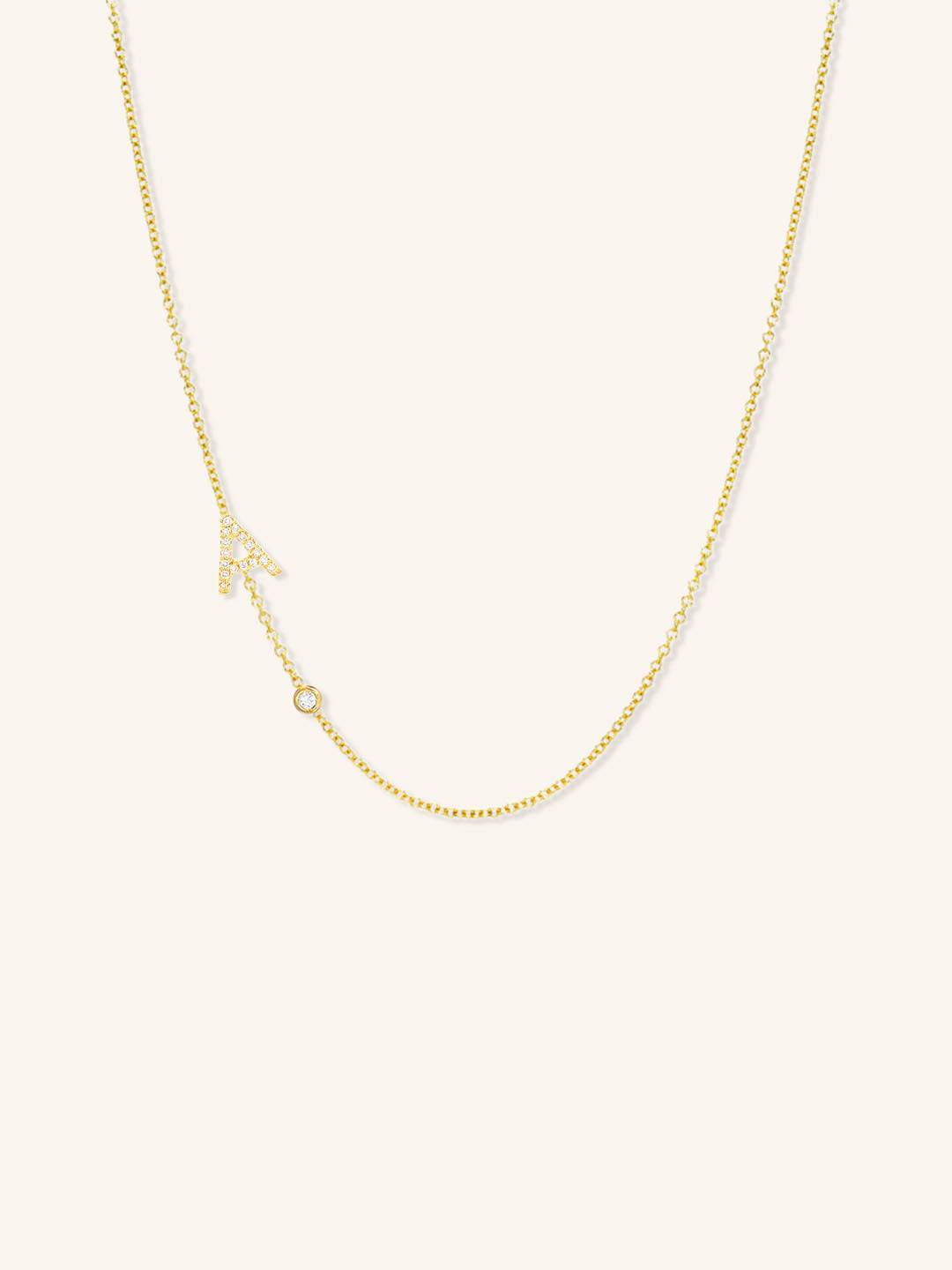 Yellow gold asymmetrical diamond initial A and bezel necklace on white background