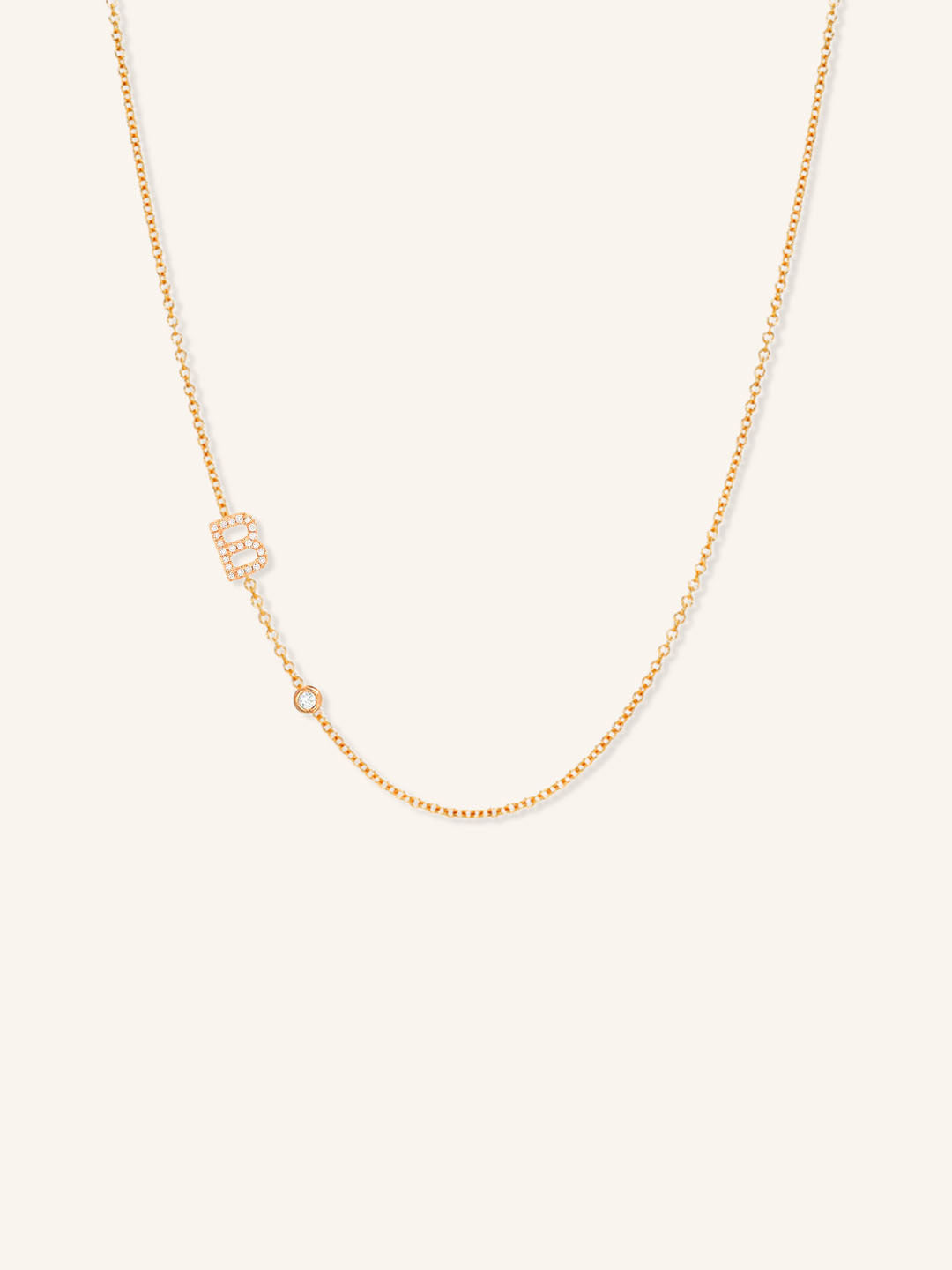 Rose gold asymmetrical diamond initial B and bezel necklace on white background