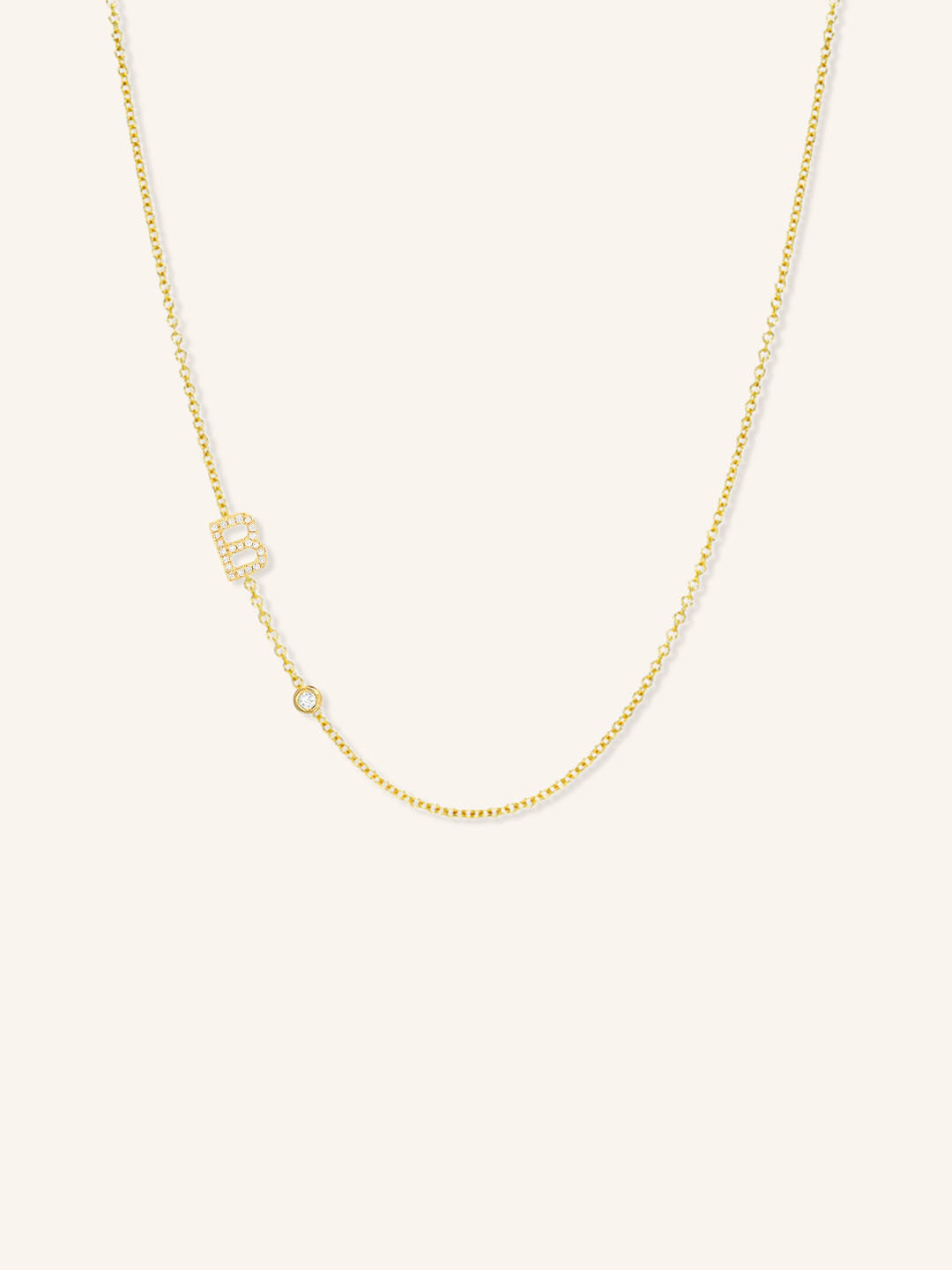 Yellow gold asymmetrical diamond initial B and bezel necklace on white background