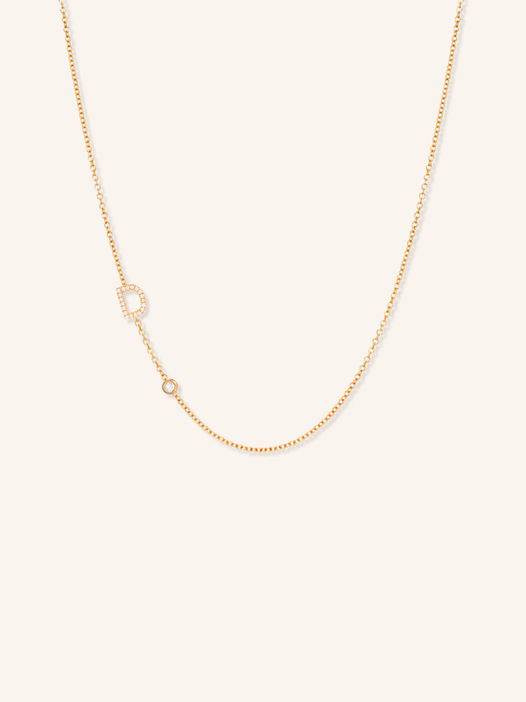 Rose gold asymmetrical diamond initial D and bezel necklace on white background