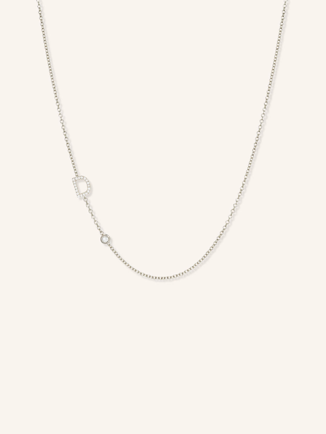 White gold asymmetrical diamond initial D and bezel necklace on white background
