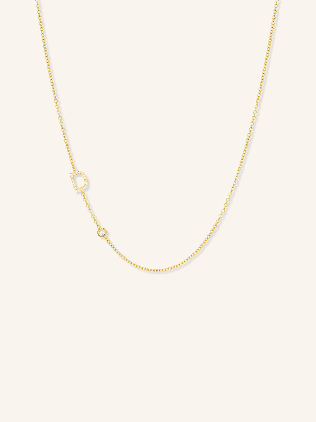 Yellow gold asymmetrical diamond initial D and bezel necklace on white background