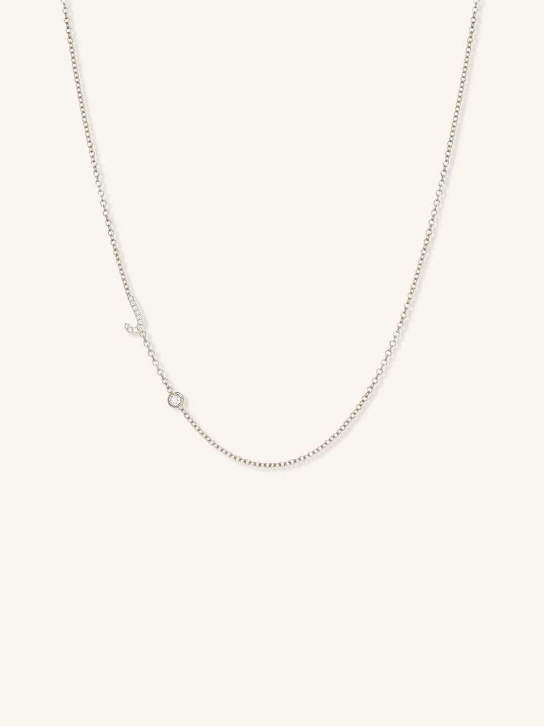 White gold asymmetrical diamond initial J and bezel necklace on white background