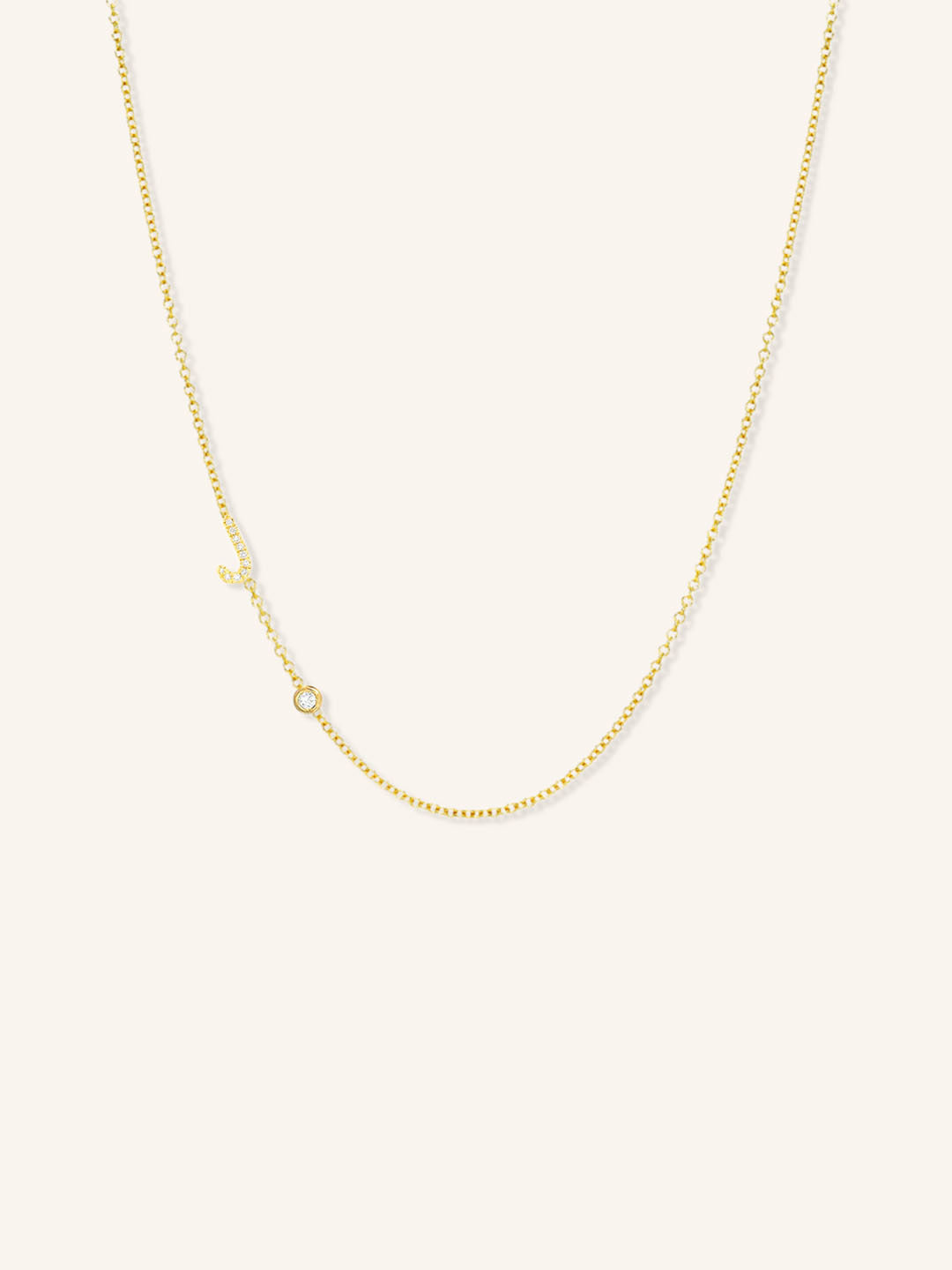 Yellow gold asymmetrical diamond initial J and bezel necklace on white background