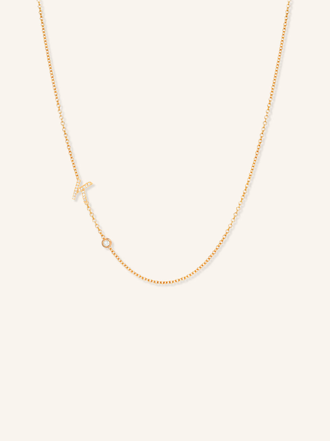 Rose gold asymmetrical diamond initial K and bezel necklace on white background
