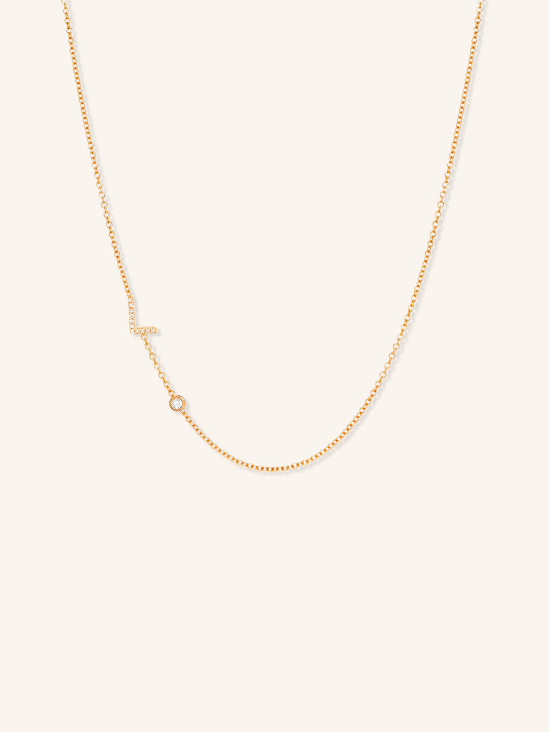 Rose gold asymmetrical diamond initial L and bezel necklace on white background