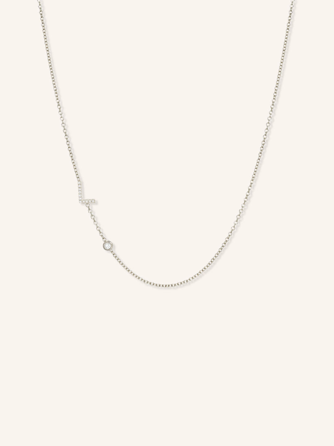 White gold asymmetrical diamond initial L and bezel necklace on white background